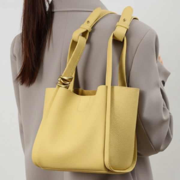 Arden Genuine Leather Bucket Bag in off-yellow, lifestyle shoulder shot showing adjustable straps, pebbled leather, and gold hardware