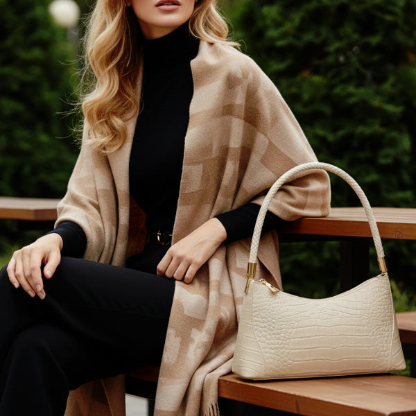 Arlena genuine cowhide shoulder bag off-white placed on a bench with model showcasing its elegant design and braided handle