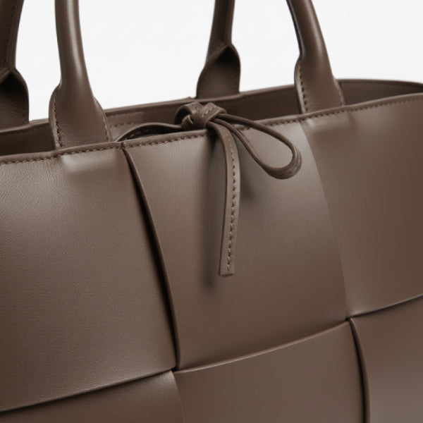 Close-up of Aurelia brown genuine leather tote bag showcasing the woven leather texture and decorative tie closure