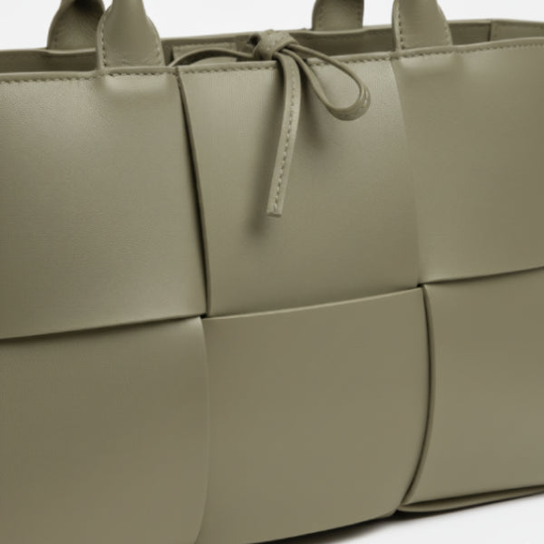 Close-up of Aurelia green genuine leather tote bag showcasing the woven leather texture and decorative tie closure