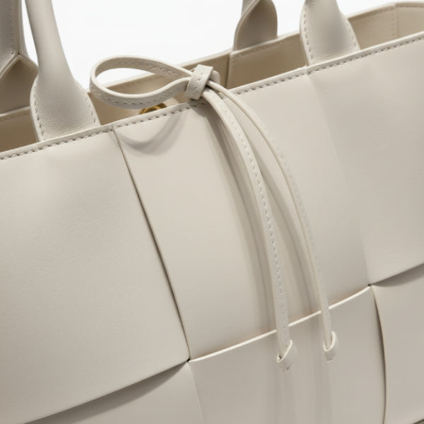 Close-up of Aurelia off-white genuine leather tote bag showcasing the woven texture and decorative tie closure