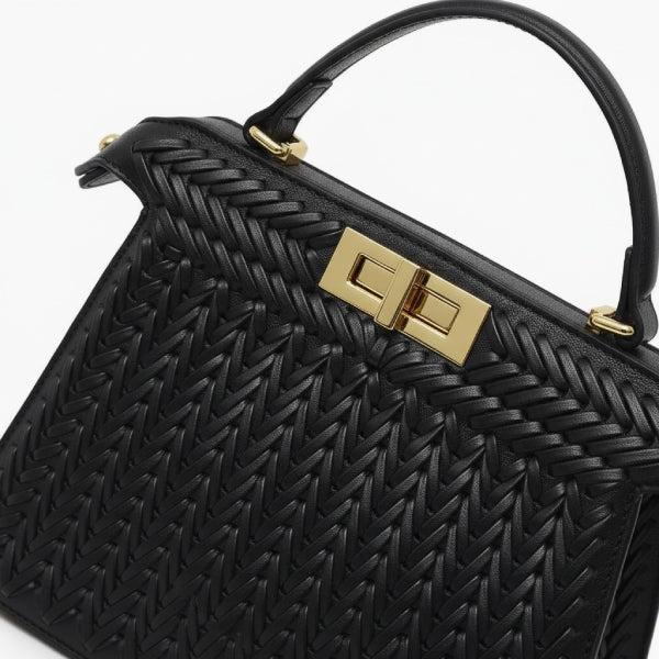 Close-up of black woven vegan leather satchel bag with gold clasp and handle detail