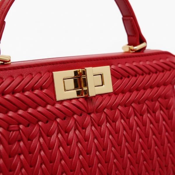 Close-up of red woven vegan leather satchel bag with gold clasp and handle detail