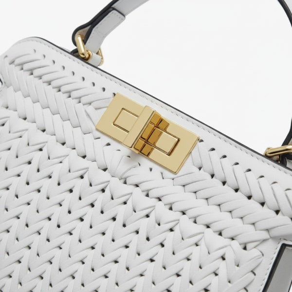 Close-up of white woven vegan leather satchel bag with gold clasp and handle detail