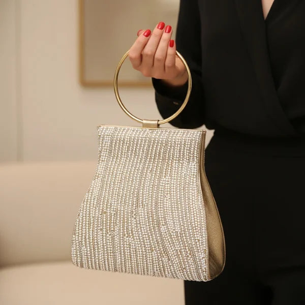 Celestia Rhinestone Crystal Evening Bag in gold, indoor lifestyle closeup with model hand-carrying to show elegant hourglass shape