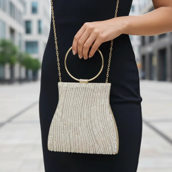 Celestia Rhinestone Crystal Evening Bag in gold, outdoor lifestyle shot with model showing circular ring handle and chain strap sparkle