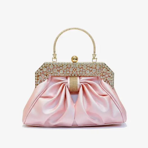 Front view of a pink vegan leather evening bag featuring a rhinestone-encrusted gold frame and pleated satin fabric