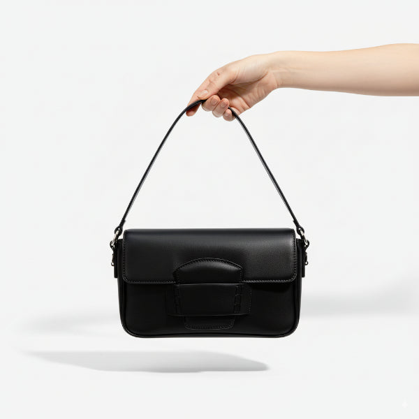 Faelina genuine cowhide shoulder bag in black held by hand, demonstrating its versatile and stylish design