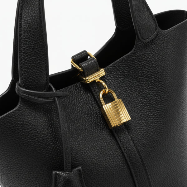 Lunelia Vegan Leather Bucket Bag in black, closeup highlighting pebbled texture, gold padlock detail, and structured twin handles