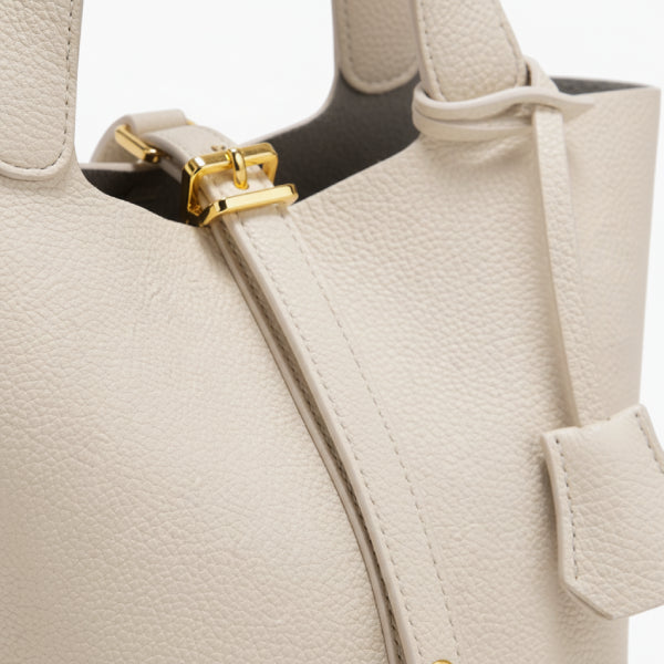 Lunelia Vegan Leather Bucket Bag in white, closeup highlighting pebbled texture, gold hardware buckle, and sleek center strap with padlock