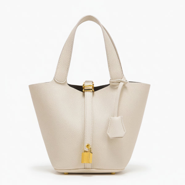 Lunelia Vegan Leather Bucket Bag in white, front studio view showcasing tapered bucket silhouette, twin handles, and gold padlock charm with base feet