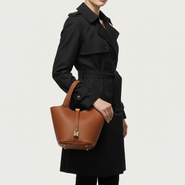 Lunelia Vegan Leather Bucket Bag in caramel, lifestyle model shot hand-carrying to show elegant medium size and refined look