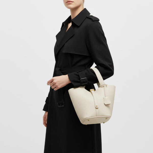 Lunelia Vegan Leather Bucket Bag in white, lifestyle model shot hand-carrying to show elegant medium size and refined minimalist style