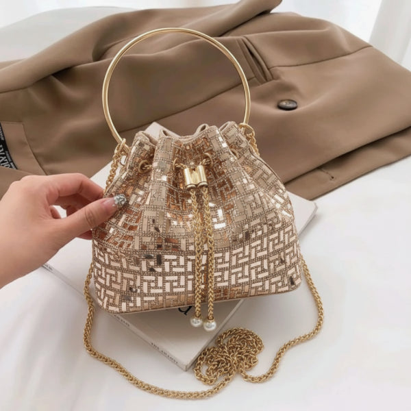 Lyanna Metallic Embellished Bucket Bag in gold, lifestyle hand-held shot showing ring handle, detachable chain strap, and sparkling finish