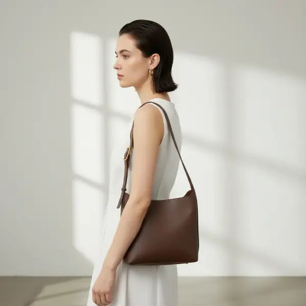 Model wearing Meliora vegan leather shoulder bag in coffee color with adjustable strap