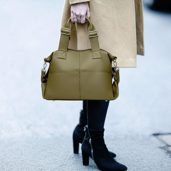 Model holding Mirelith olive green leather satchel bag with quilted handles and adjustable straps, styled with a beige coat and black boots
