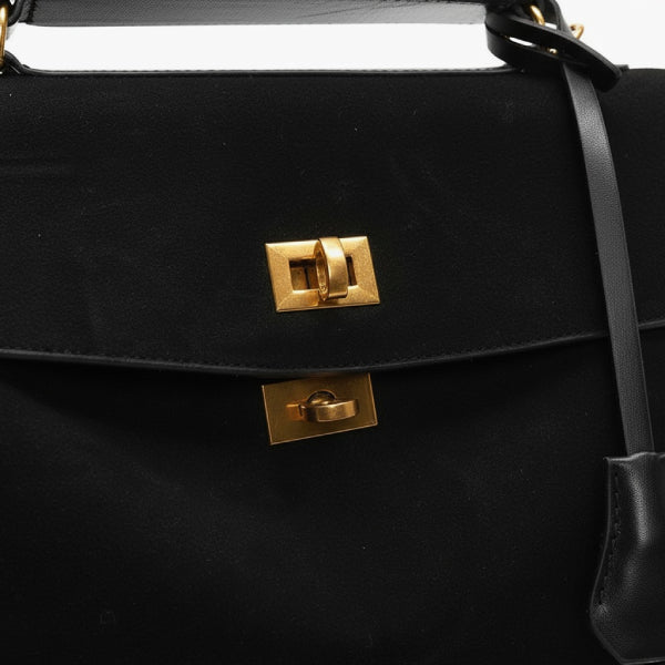 Close-up of black velvet satchel bag with gold metal clasp and lock detailing