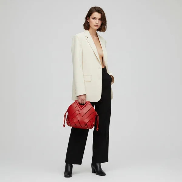 Seren Vegan Leather Bucket Bag in red, lifestyle full-body shot with model hand-carrying to show bold size and modern silhouette