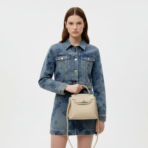 Female model in a denim jacket and skirt, holding an off-white genuine leather satchel bag with silver clasp, perfect for a casual yet refined look