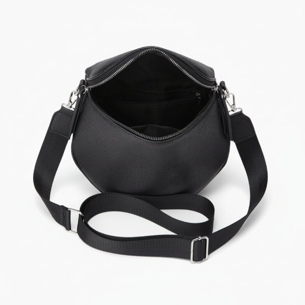 Interior view of a black vegan leather crossbody bag showcasing the zipped compartment and smooth lining