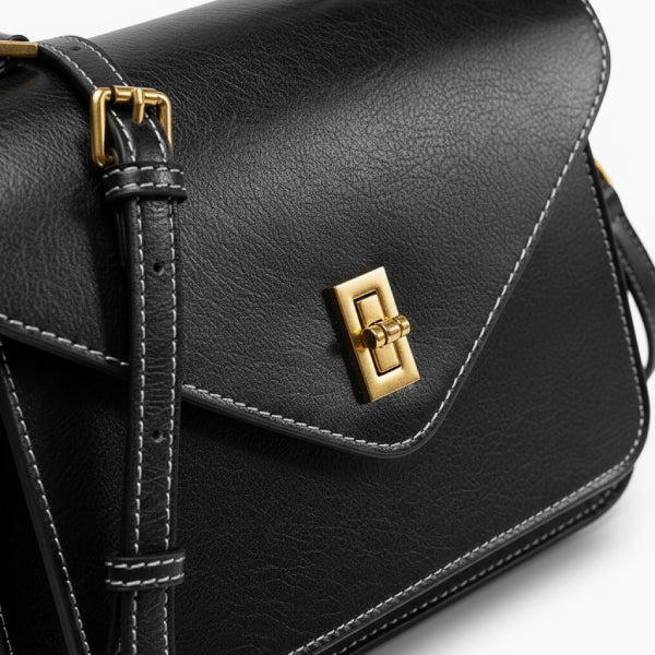 Close-up of the gold-tone clasp and fine stitching on the black genuine leather satchel bag, highlighting its sleek and sophisticated design