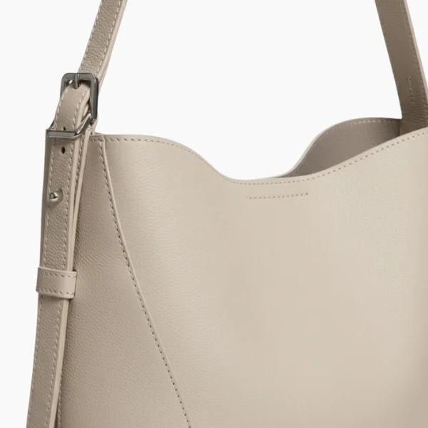 Amara Vegan Leather Bucket Bag in off-white, side closeup highlighting pebbled vegan leather, clean stitching, and adjustable buckle strap