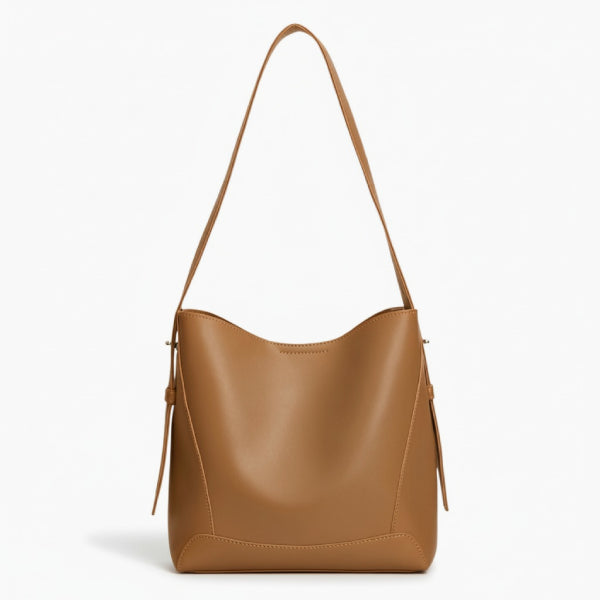 Amara Vegan Leather Bucket Bag in brown, front studio view showcasing minimalist bucket silhouette and wide shoulder strap