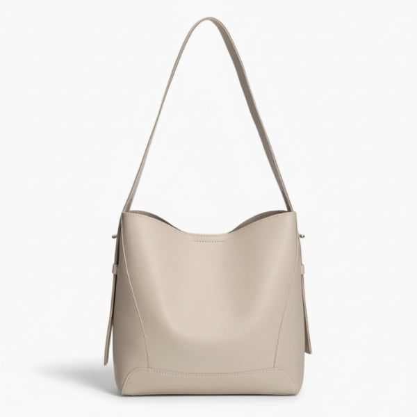 Amara Vegan Leather Bucket Bag in off-white, front studio view showcasing minimalist bucket silhouette and wide shoulder strap