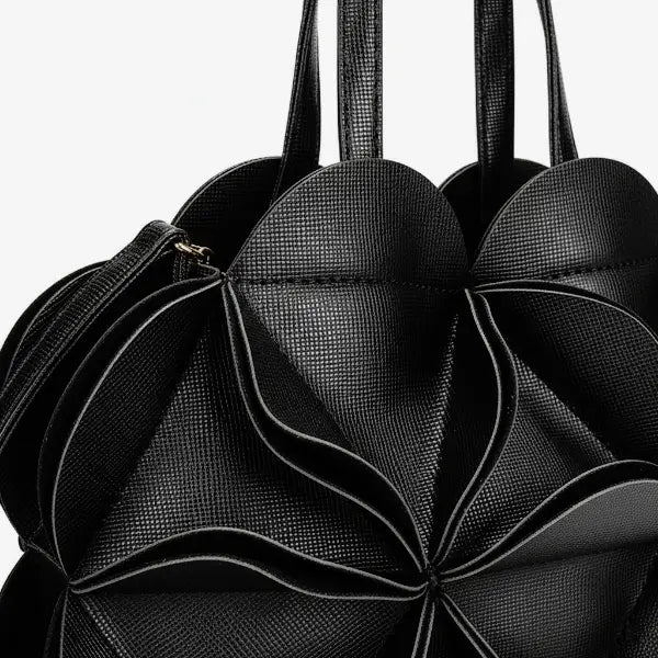 Close-up of a black vegan leather evening bag with intricate pleating creating a flower pattern