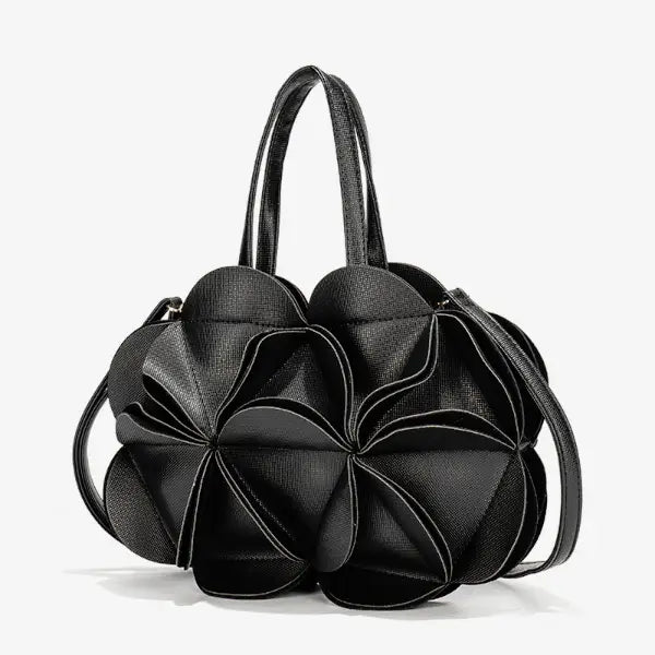 Front view of a black vegan leather evening bag featuring a large, flower-shaped design with geometric pleats and two top handles