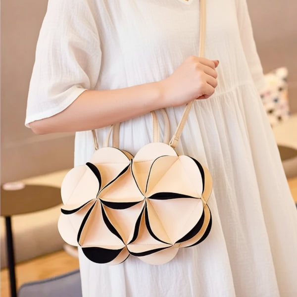 Model holding a beige vegan leather evening bag with a unique flower pattern and top handles