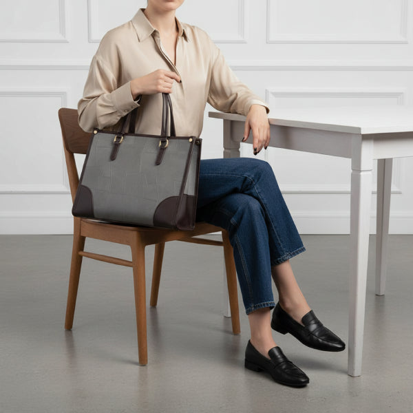 Anelisse vegan leather tote bag in grey worn by model, showing its sophisticated design with brown leather accents and gold-tone hardware