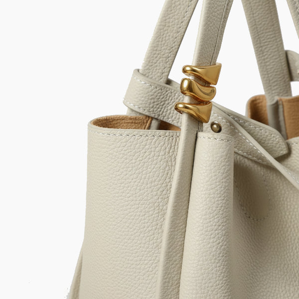 Arden Genuine Leather Bucket Bag in off-white, closeup of pebbled leather with gold hardware and adjustable strap