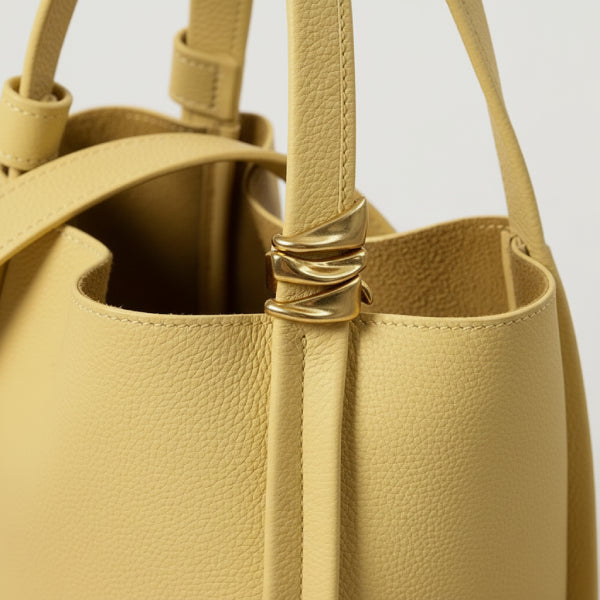 Arden Genuine Leather Bucket Bag in off-yellow, closeup highlighting pebbled leather texture and sculptural gold hardware
