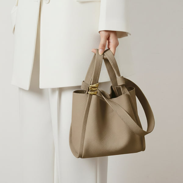 Arden Genuine Leather Bucket Bag in beige, lifestyle shot with model hand-carrying and shoulder strap showing size and elegant shape