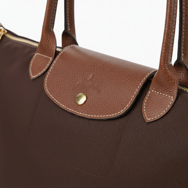 Close-up of Aria brown vegan leather tote bag showing the brown leather flap with button closure and stitching details