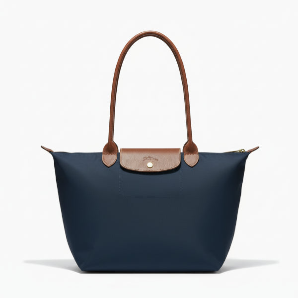 Front view of Aria navy blue vegan leather tote bag with brown leather handles and flap design