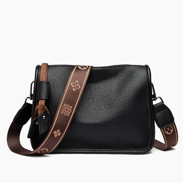 Auralis Genuine Cowhide Crossbody Bag in black, front studio view showcasing rectangular silhouette, zip-top closure, and patterned adjustable strap