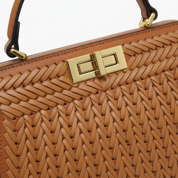 Close-up of brown woven vegan leather satchel bag with gold clasp and handle detail