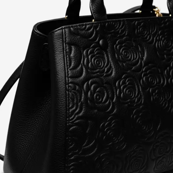 Close-up of Azura black leather satchel bag with embossed rose pattern and gold clasp details