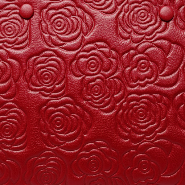 Close-up of Azura red leather satchel bag with embossed rose pattern and gold clasp details