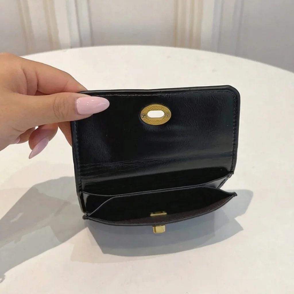 Black wallet with gold accents held by a hand on a white surface