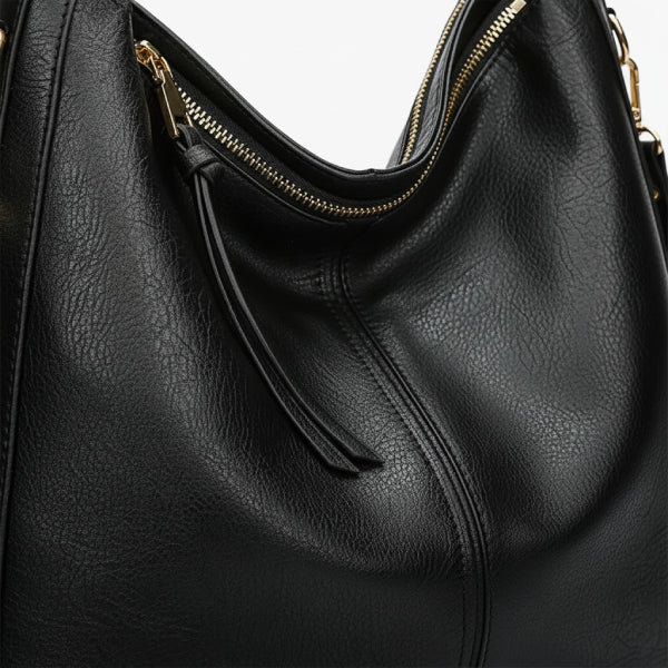 Close-up of black vegan leather shoulder bag with gold zipper detailing and shoulder straps