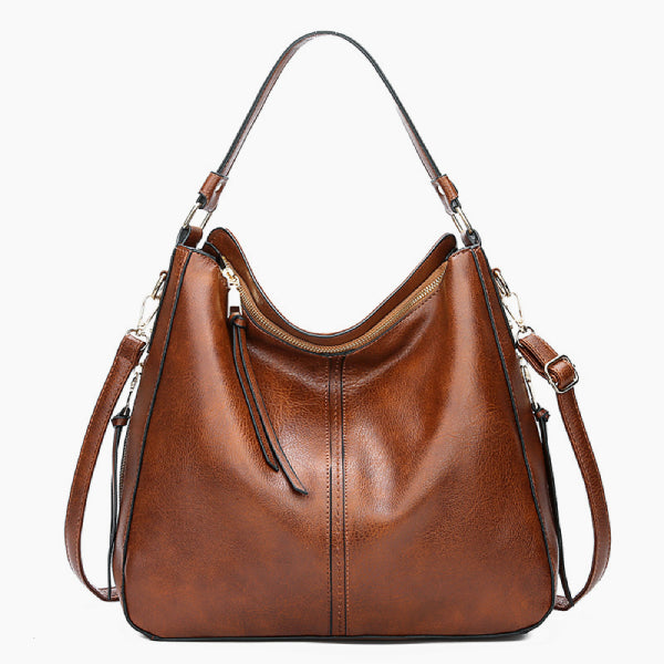 Front view of brown vegan leather shoulder bag with a sleek design, gold zipper, and handles