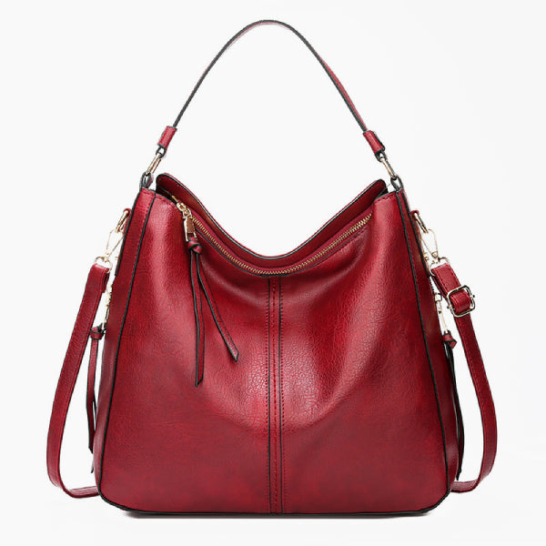 Front view of red vegan leather shoulder bag with a sleek design, gold zipper, and handles