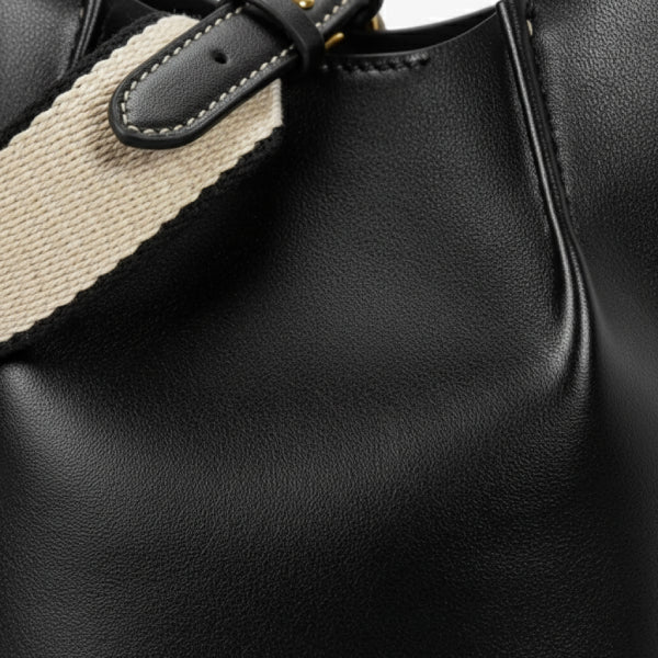 Calypso Vegan Leather Crossbody Bag in black, closeup highlighting sleek vegan leather, contrast stitching, and adjustable canvas strap detail