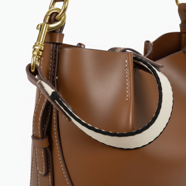 Calypso Vegan Leather Crossbody Bag in brown, closeup highlighting sleek vegan leather, contrast stitching, and detachable strap clips
