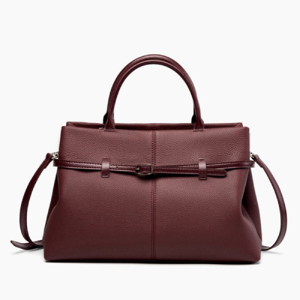 Front view of a wine red genuine leather tote bag with a sleek and sophisticated design, highlighted by the central buckle accent