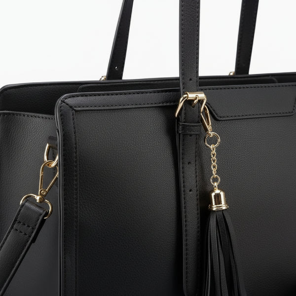 Close-up of Clea black polyester tote bag showing the gold hardware, zipper pull, and handle detailing