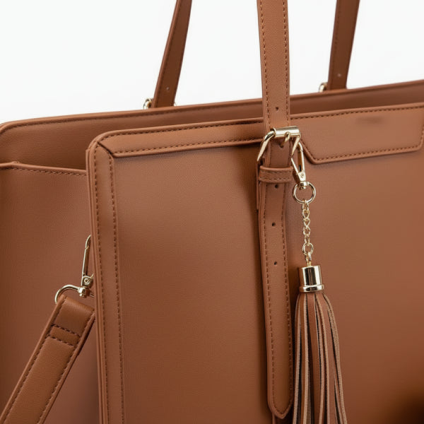 Close-up of Clea brown polyester tote bag showing the tassel detail, gold hardware, and smooth leather texture